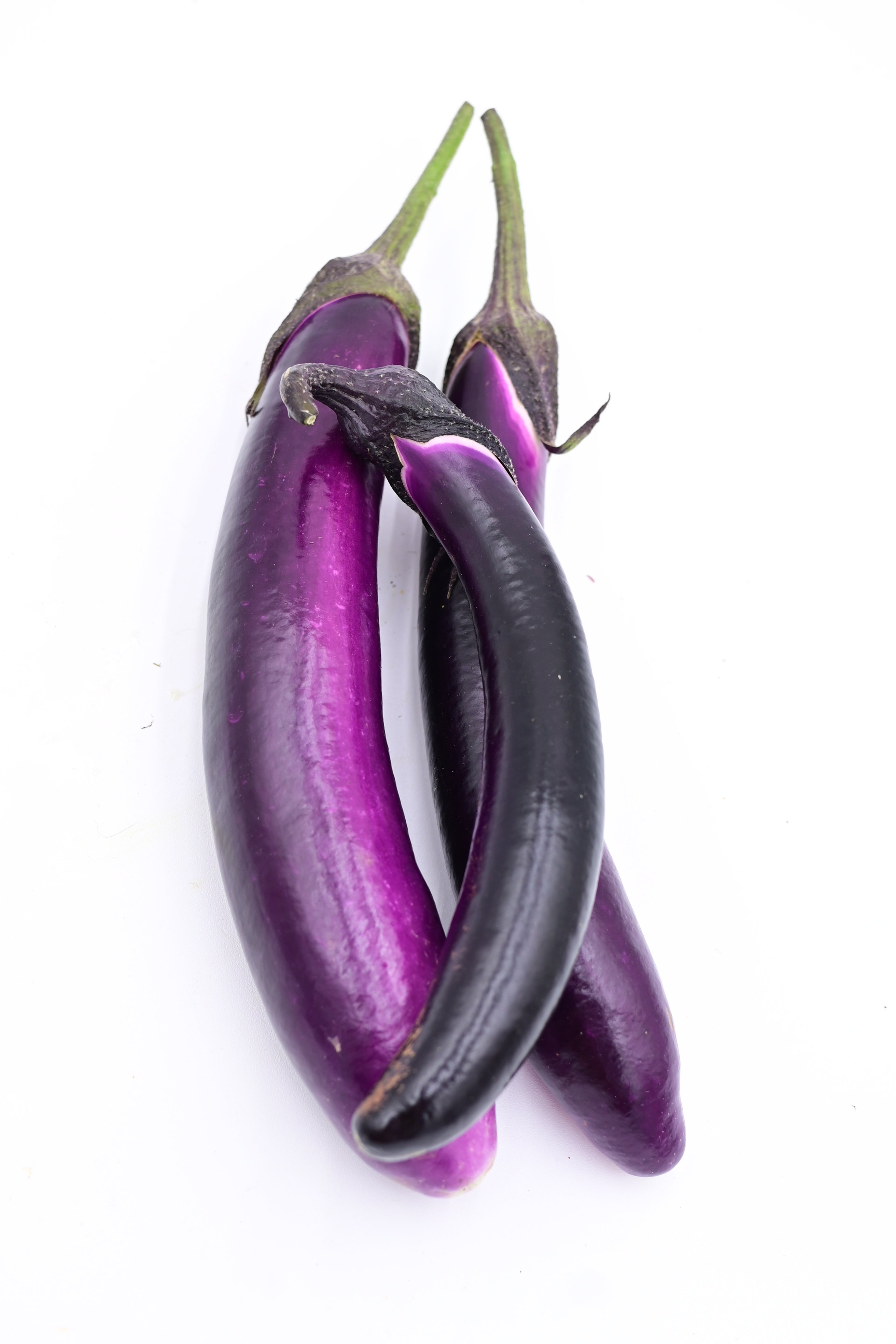 A trio of slender purple eggplant on a white background.